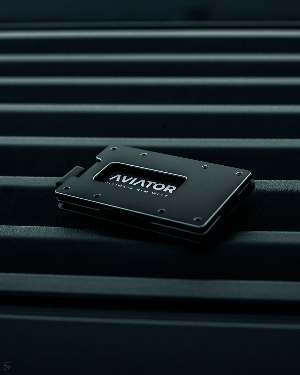 Un portafoglio minimalista in metallo nero appoggiato su una superficie a coste.