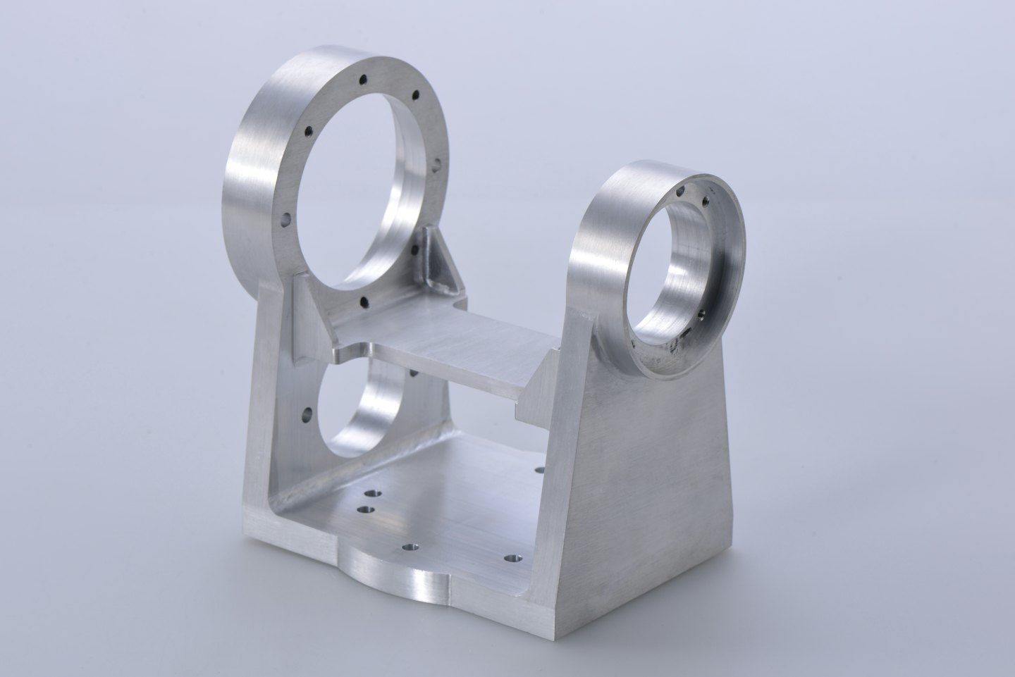 Componente metallico lavorato con fori per bulloni in uno studio.