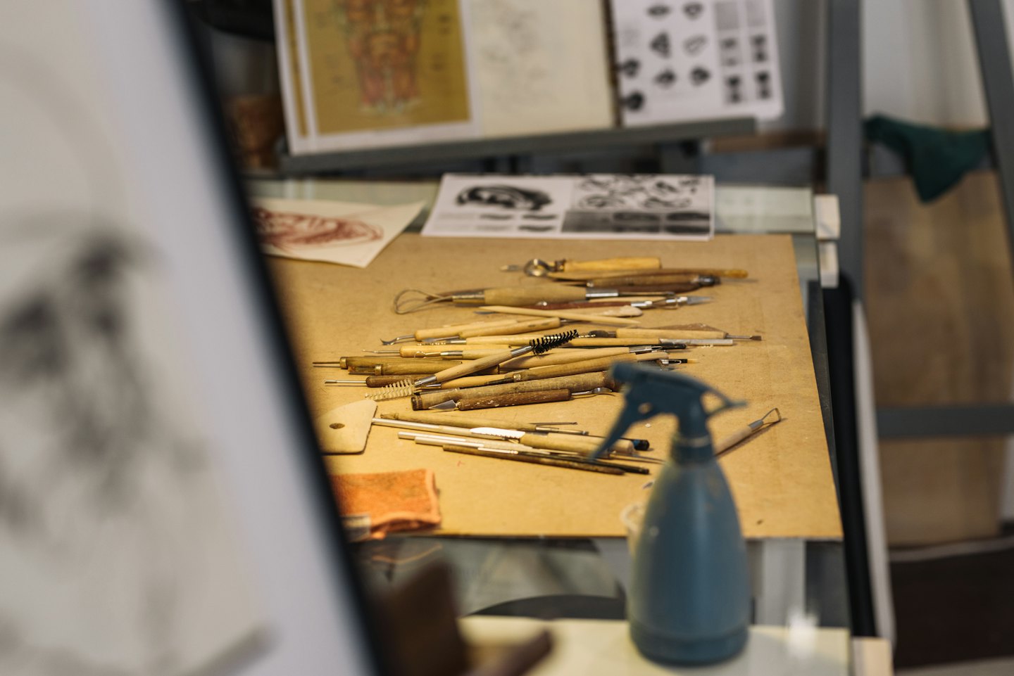 Attrezzi da scultura con manici in legno disposti su una superficie di lavoro da studio.
