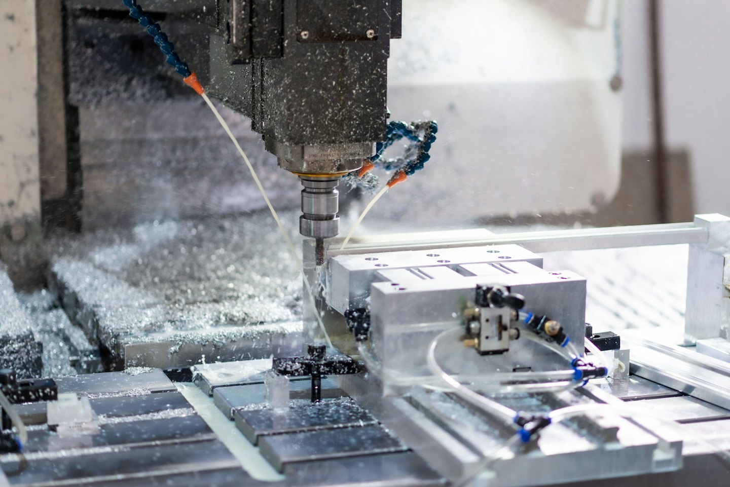 Fresatrice CNC che taglia un pezzo metallico con refrigerante.