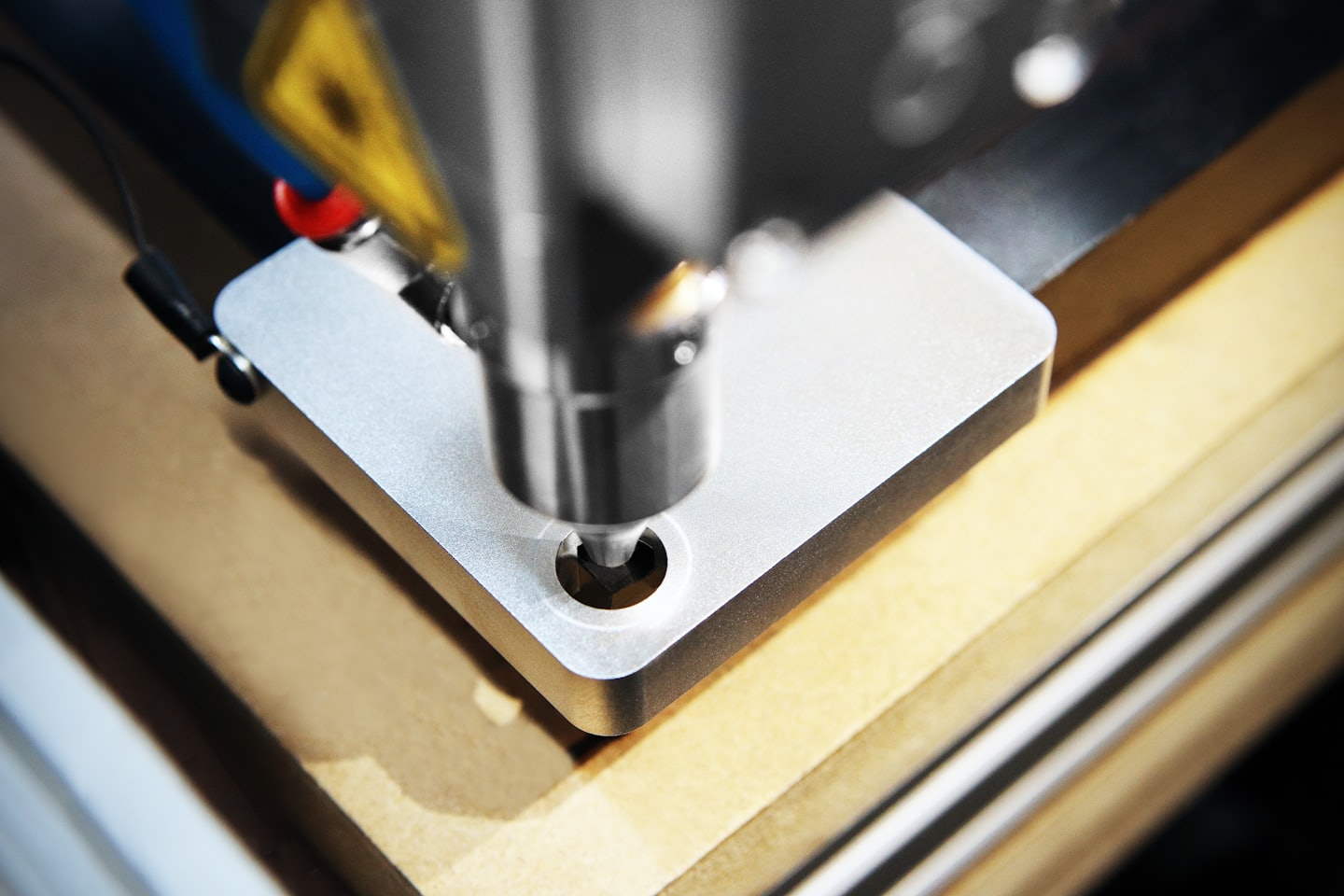 Fresatrice CNC che crea un foro rotondo in legno di colore marrone chiaro.