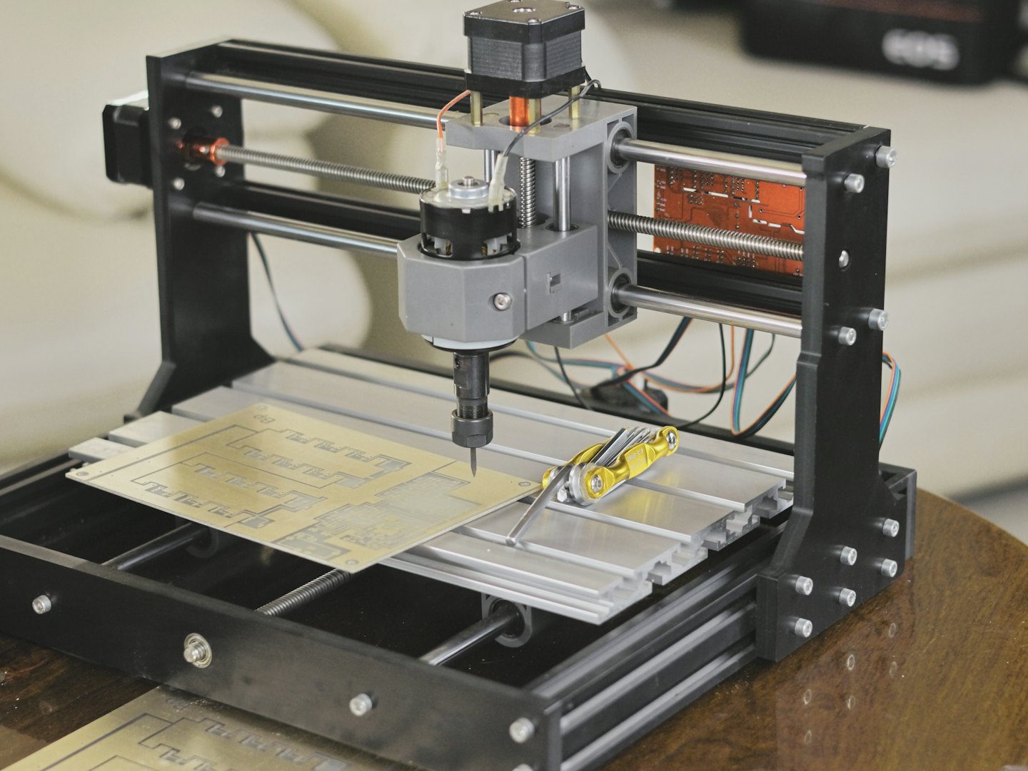 Macchina CNC da banco incide un circuito stampato su un tavolo.