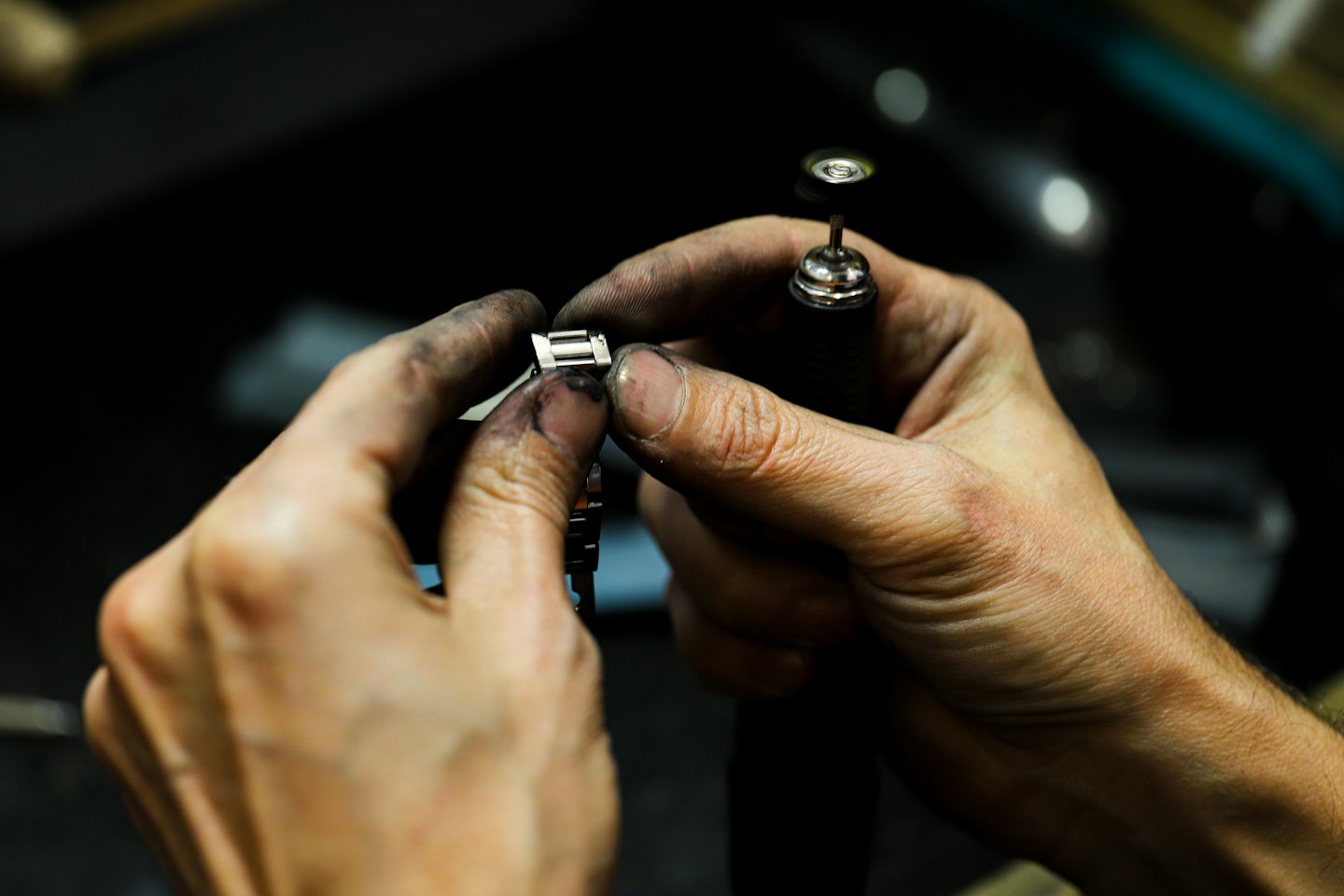 Un artigiano usa un utensile rotante per lucidare un bracciale metallico per orologi.